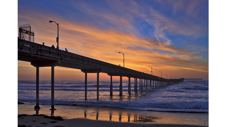 The Ocean Beach Municipal Pier under a colorful sunset with clouds