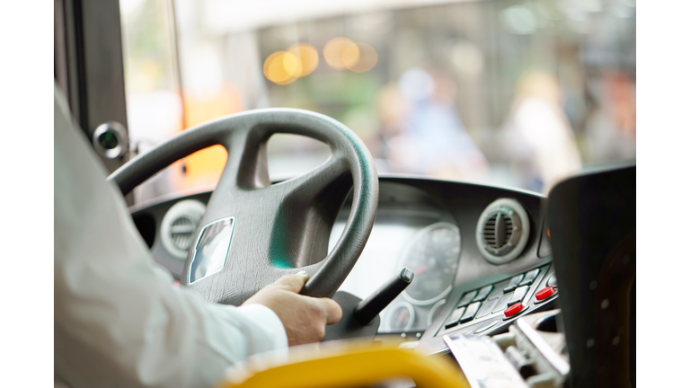 cropped shot of bus driver holding steering whee