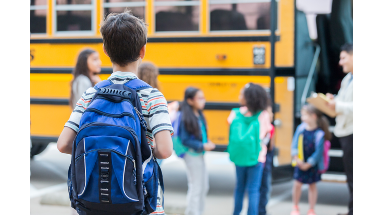 Young boy waits to load school bus