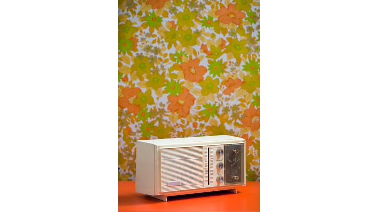 Vintage 60's 70's Clock Radio with floral wallpaper background orange