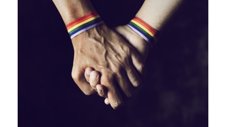 men holding hands with rainbow-patterned wristband