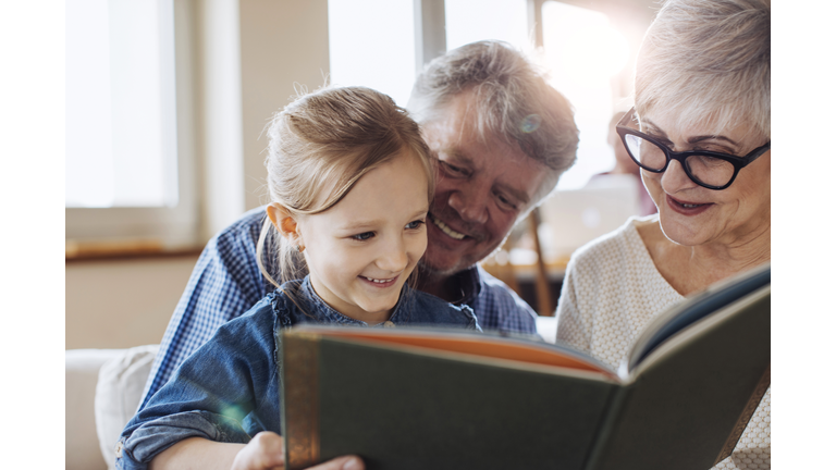 Grandparents reading a book to their beautiful granddaughter