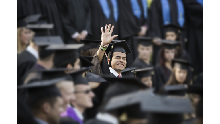 College graduate waving