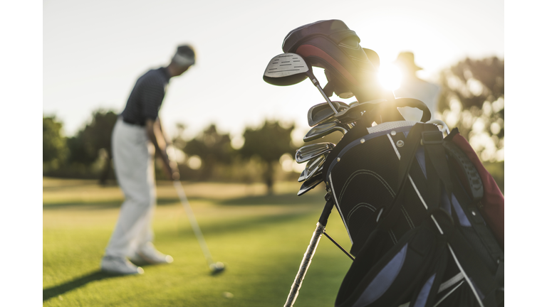 Close-up of golf bag with people in background