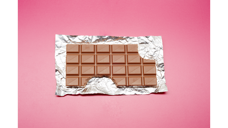 High angle view of chocolate bar on foil and pink background