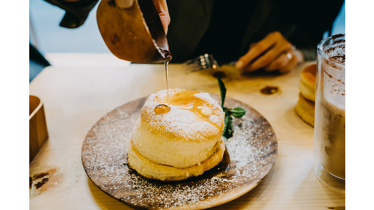 Close up of woman drown the souffle pancake in maple syrup