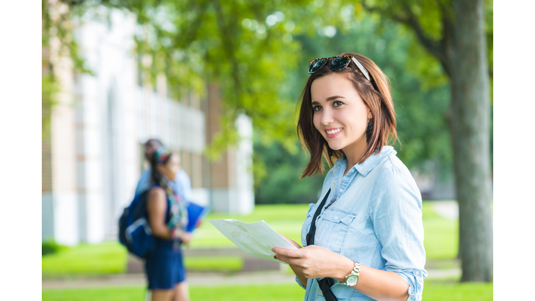 Happy college student using campus man while walking to class