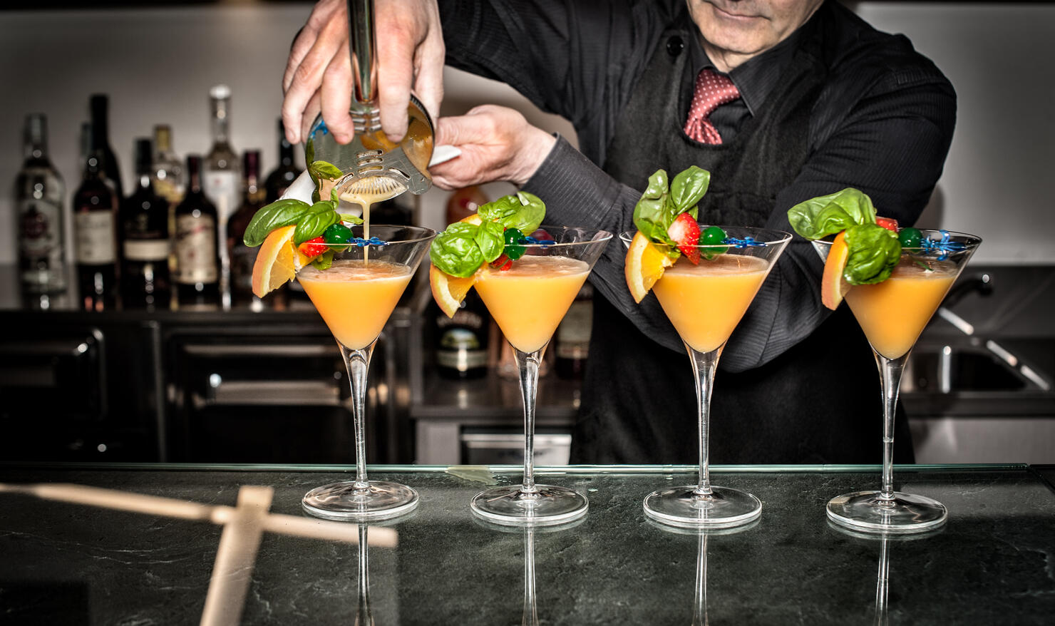 Barman pouring cocktails, mid section