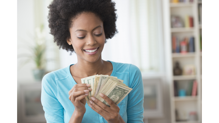 African American woman counting money in living room