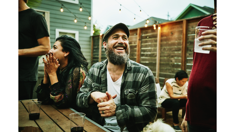 Laughing friends hanging out together during backyard dinner party