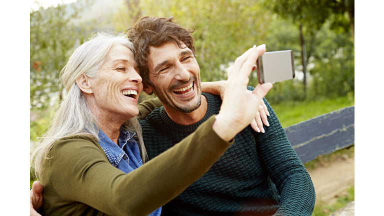 Cheerful mother and son taking selfie in park