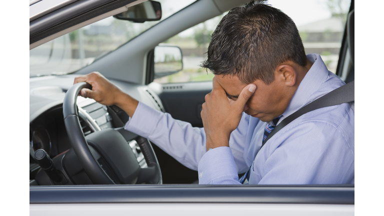 Frustrated Hispanic businessman driving in traffic