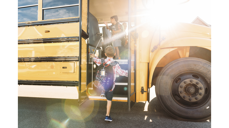 Rear view of schoolboy stepping on bus