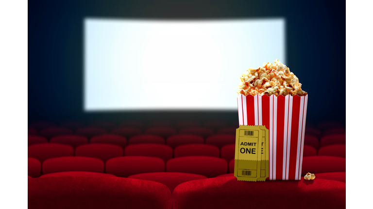 Cinema seat and pop corn facing empty movie screen