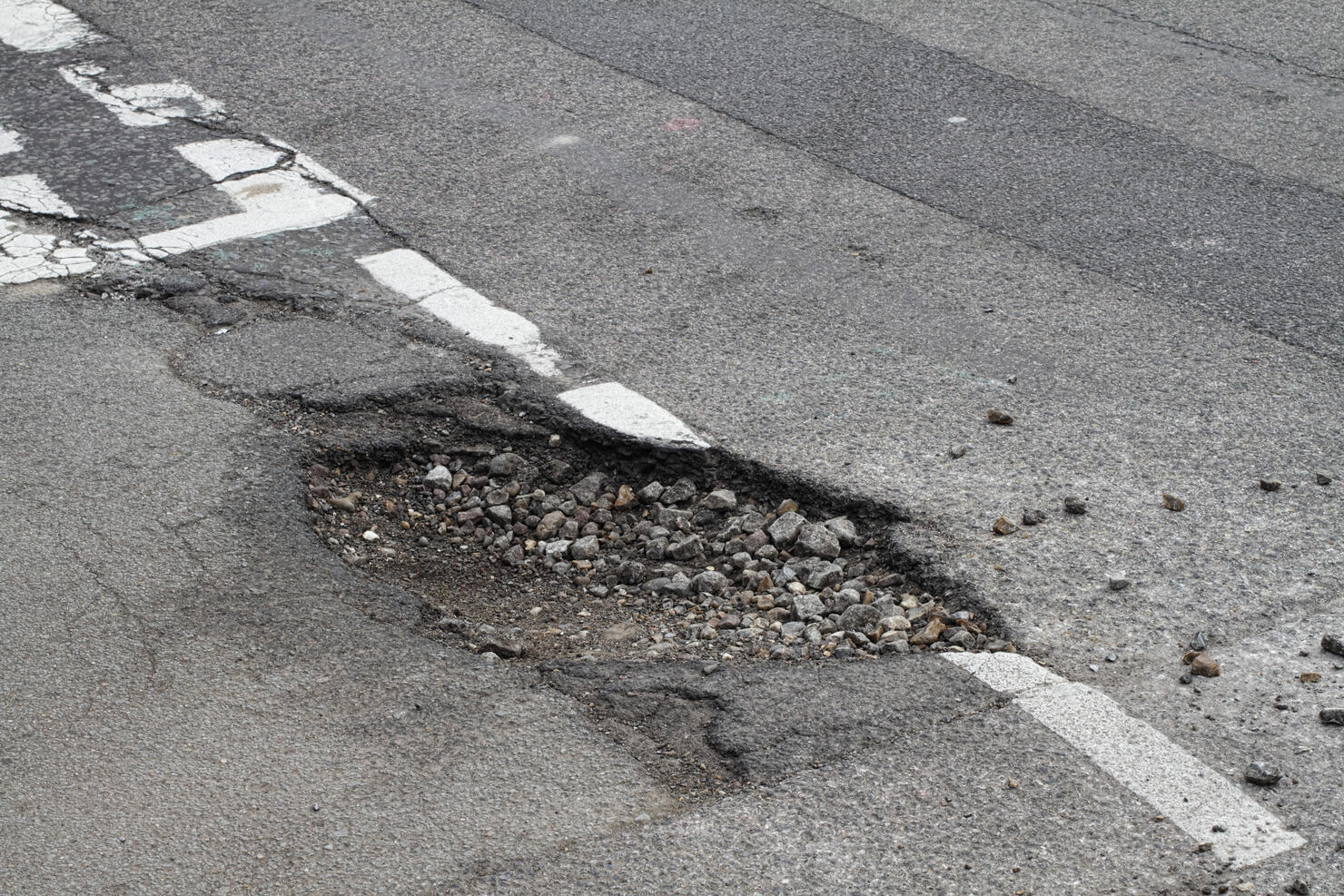 Bad repair pothole in road T-junction suffers frost damage