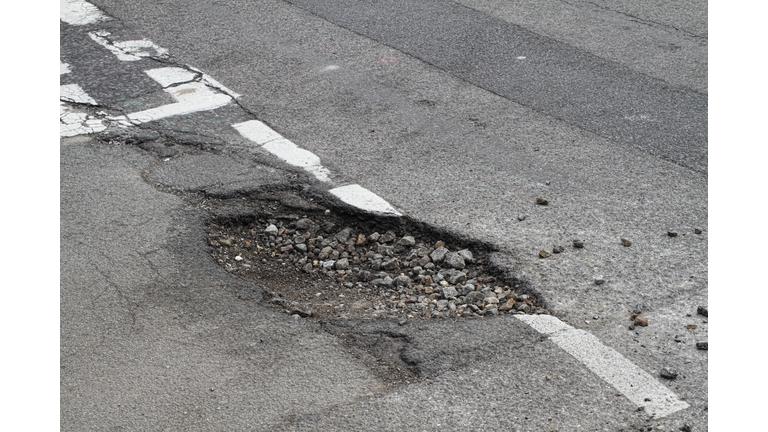 Bad repair pothole in road T-junction suffers frost damage