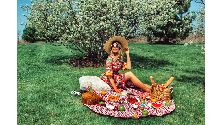 Smiling Woman Enjoying Picnic On Field At Park