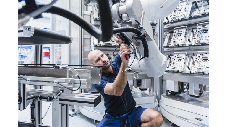 Man working at industrial robot in modern factory