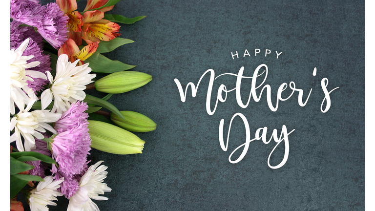 Happy Mother's Day calligraphy holiday script over dark blackboard background with beautiful colorful white, pink, orange, purple and green flower blossom bouquet