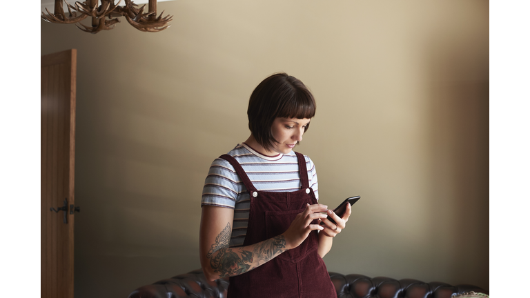 Young woman in her living room texting