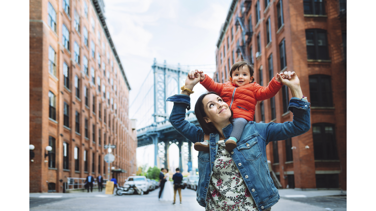 USA, New York, New York City, Mother and baby in Brooklyn with Manhattan Bridge in the background