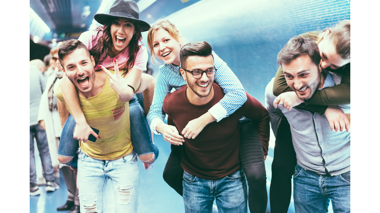 Group of friends having fun in underground metropolitan station - Young people hanging out ready for party night - Friendship and youth lifestyle concept - Focus on center girl face