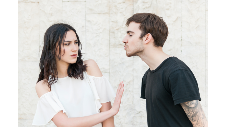 Young man trying to kiss a young woman