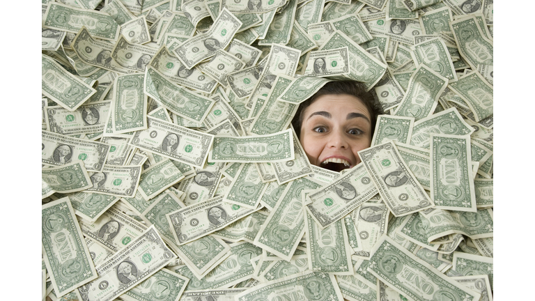 Woman's face peeking out of a pile of money