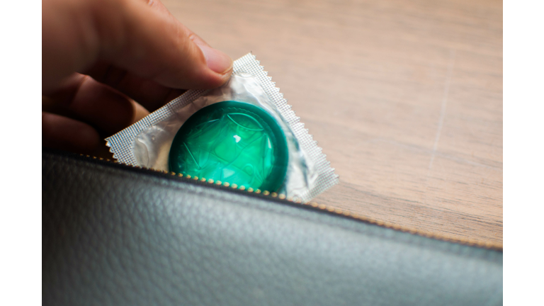 Close up of young man's hand holding a condom from wallet