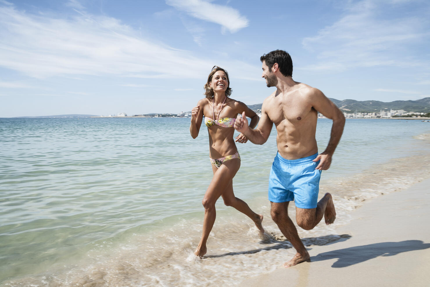 Spain, Mid adult couple running on beach