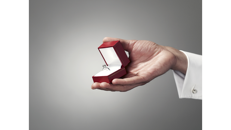 Man holding engagement ring, close-up of hand