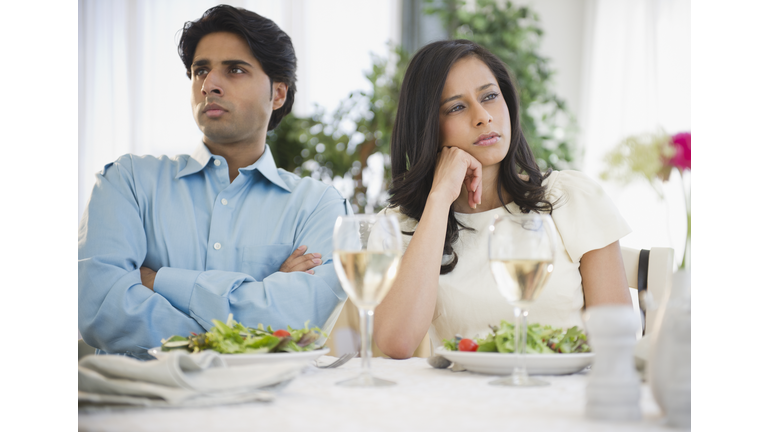Unhappy mixed race couple dining together