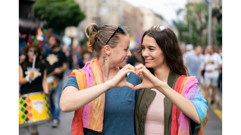 Two girlfriends making heart with their hands on the street