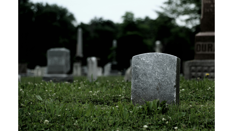 Tombstones On Grassy Field In Cemetery Against Sky