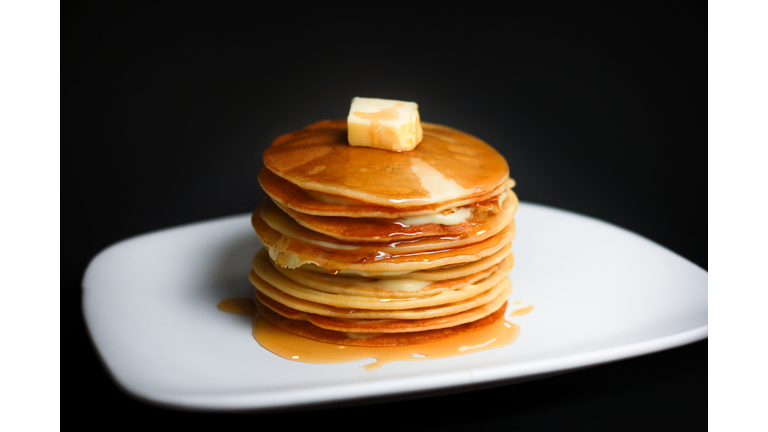 Close-Up Of Pancakes With Butter In Plate Against Black Background