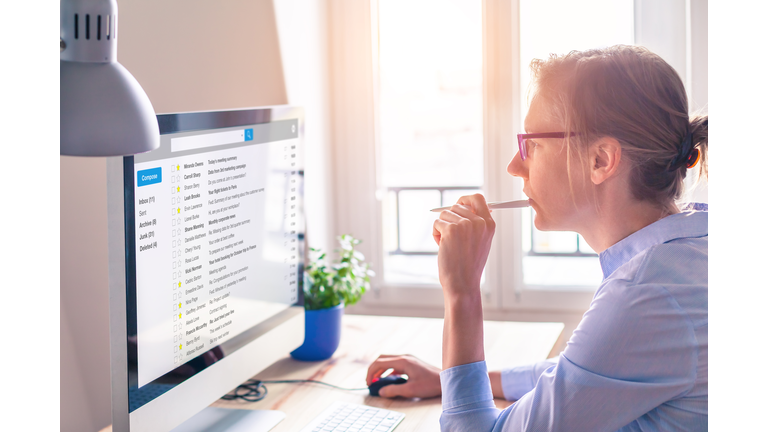 Female business person reading email on computer screen at work