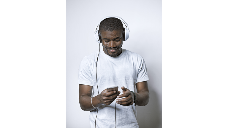 Smiling young man with headphones looking at cell phone