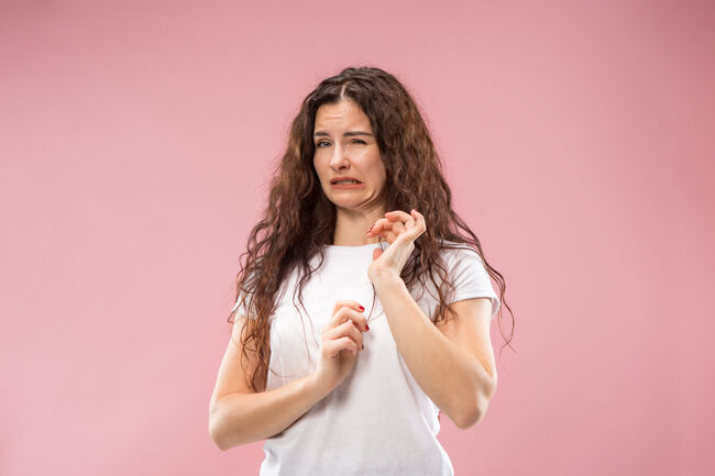 Young woman with disgusted expression repulsing something, isolated on the pink
