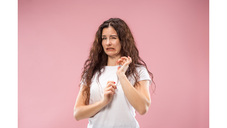 Young woman with disgusted expression repulsing something, isolated on the pink