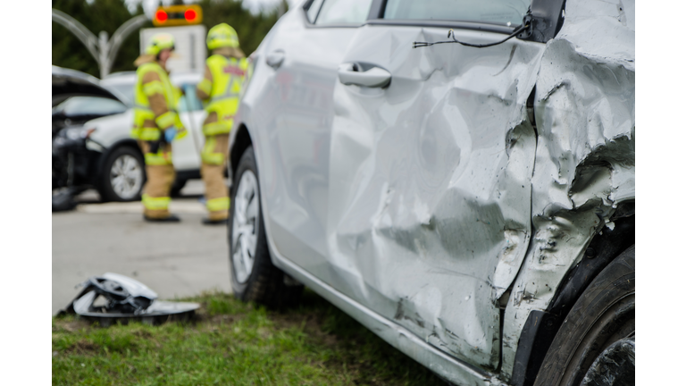 Close up on a car crashed with fireman in background