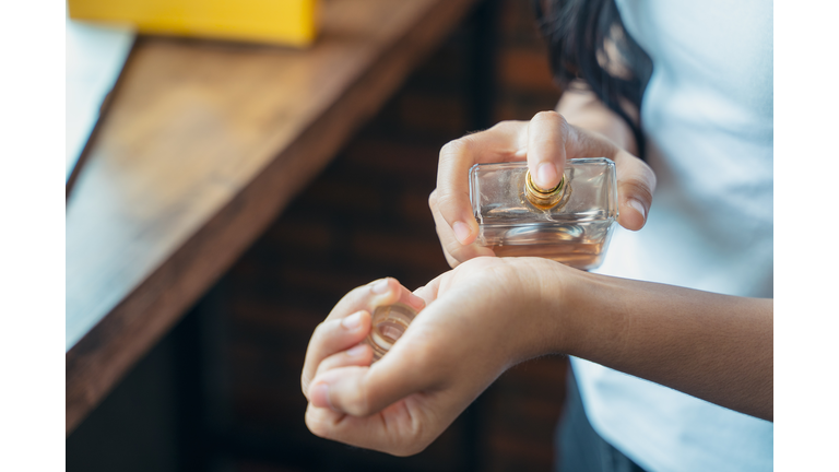 Beautiful young woman with bottle of perfume at home.