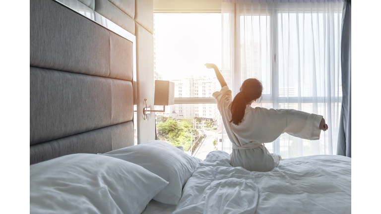 Hotel room comfort with good sleep easy relaxation lifestyle of Asian girl on bed have a nice day morning waking up, taking some rest, lazily relaxing in guest bedroom in city hotel