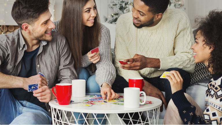 Happy friends playing game of cards UNO