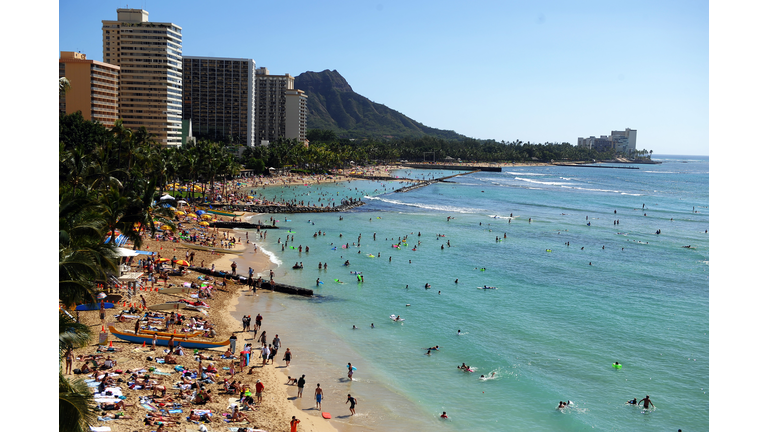 Tourists enjoy sunbathing, surfing, boat