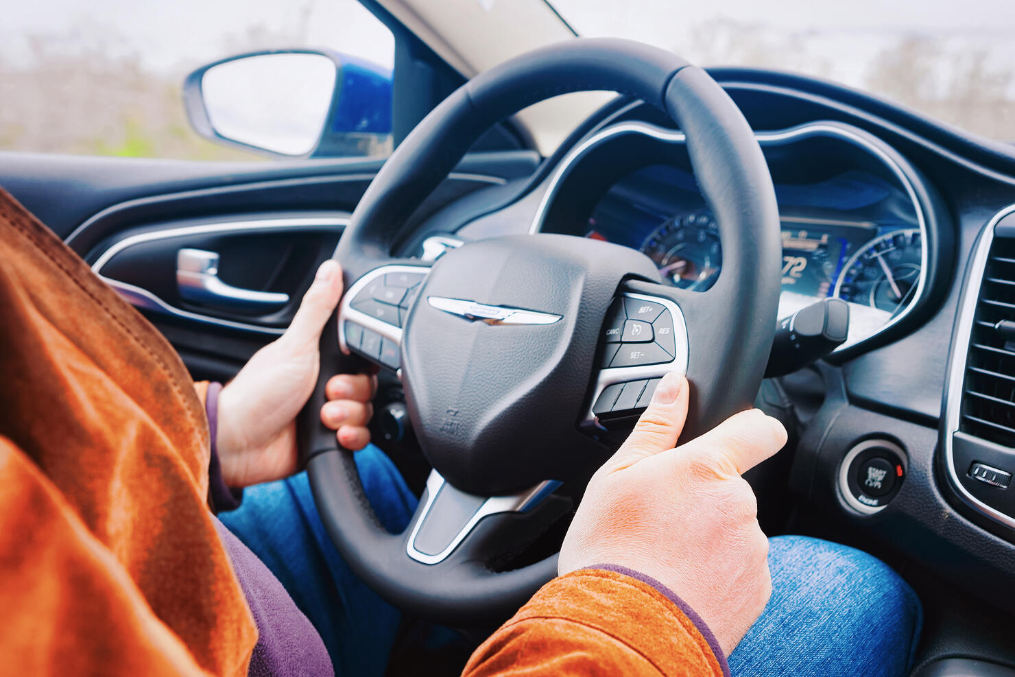 Man hands holding steering wheel of Chrysler car