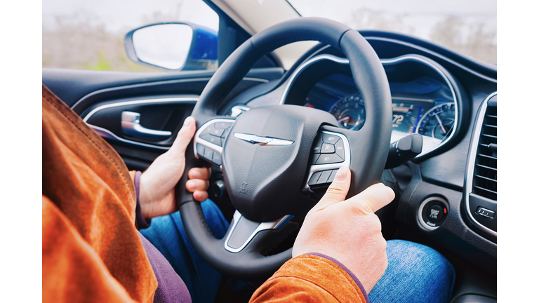 Man hands holding steering wheel of Chrysler car