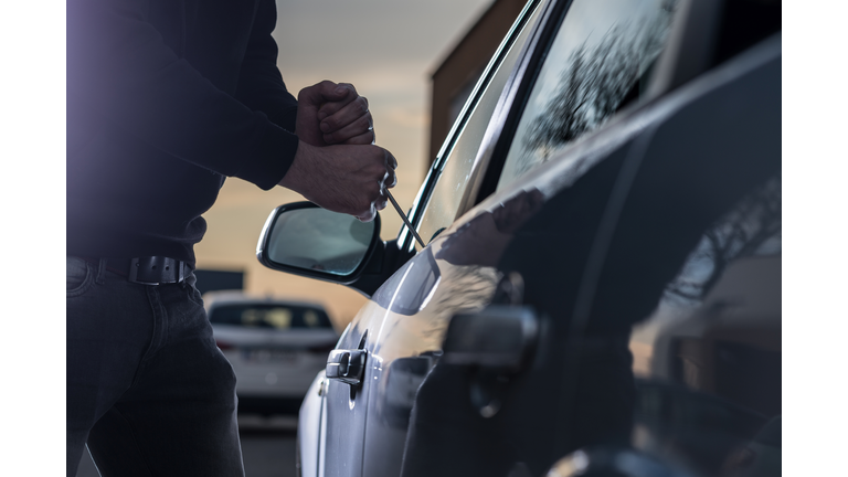 Auto thief in black balaclava trying to break into car