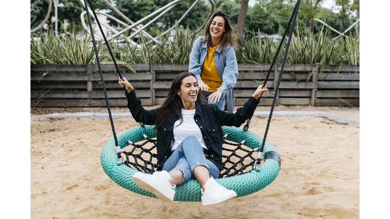 Two friends on playground, woman on a swing