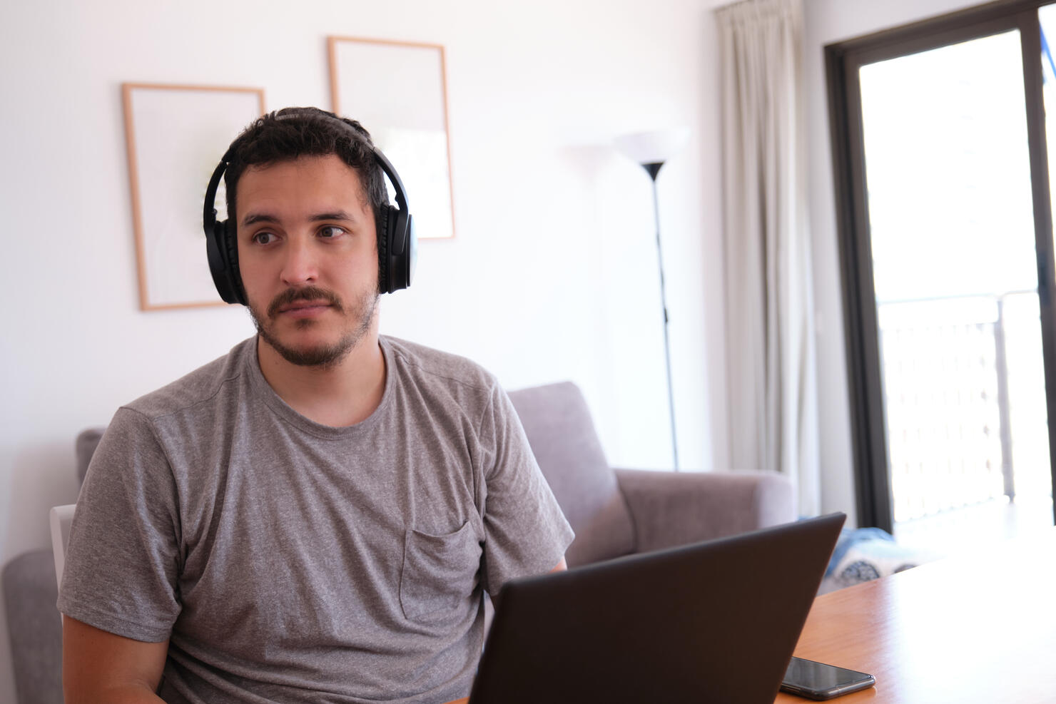 Young man wearing headphones distracted watching series, videos, instead his online classes