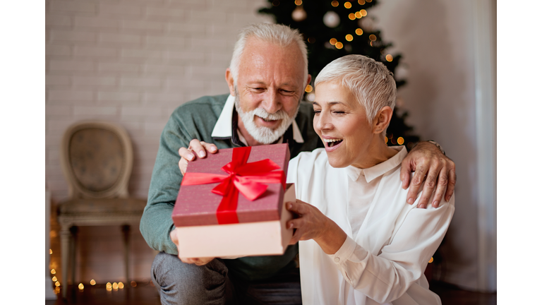 Elderly man giving a Christmas present to his wife